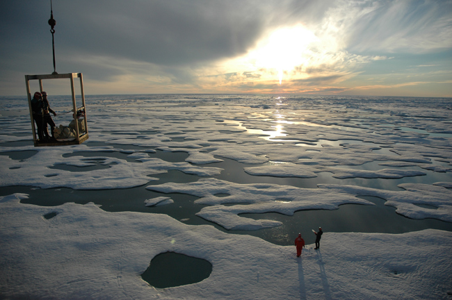 Science team descending onto the ice below in a manlift